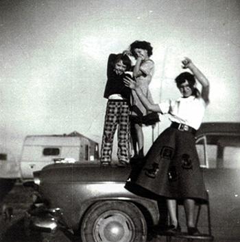 Elaine, Linda and Peggy standing on a car